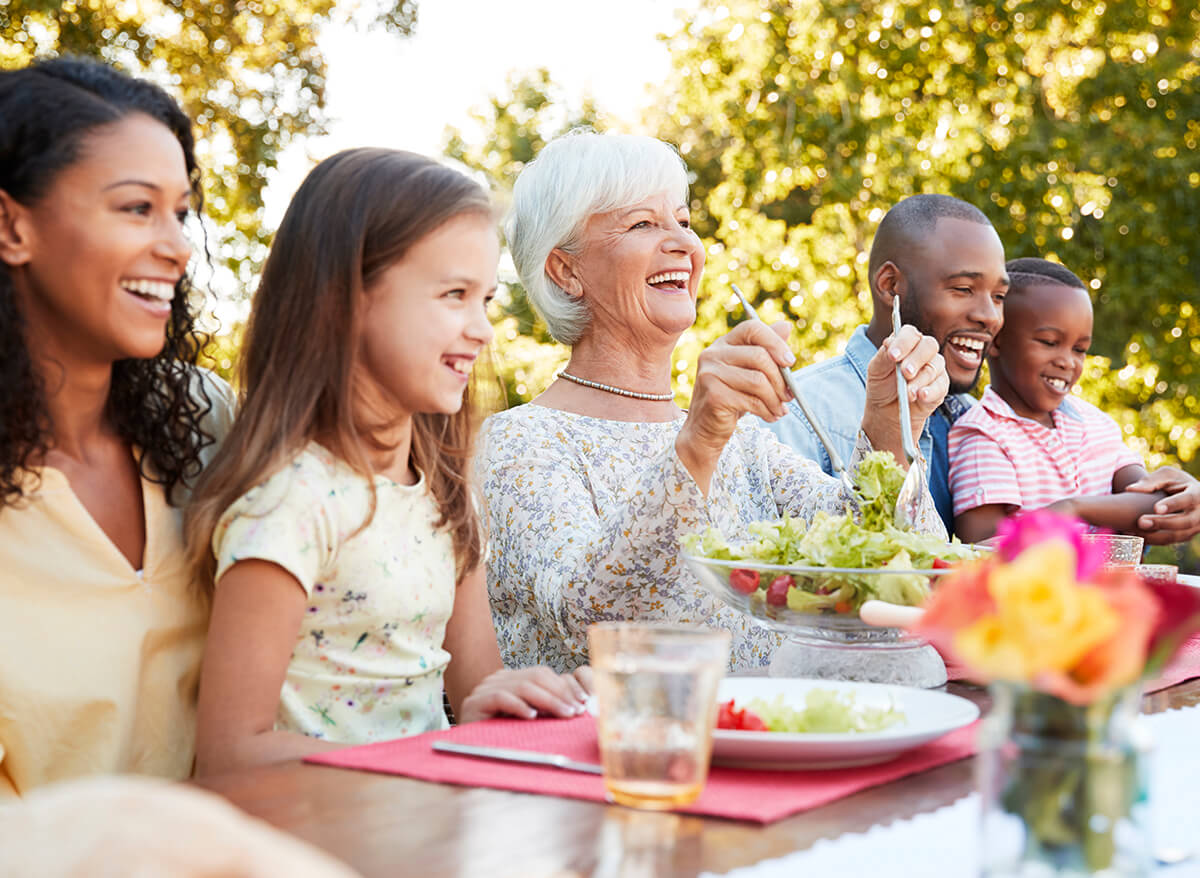 Mature woman surrounded by friends and family over outdoor lunch