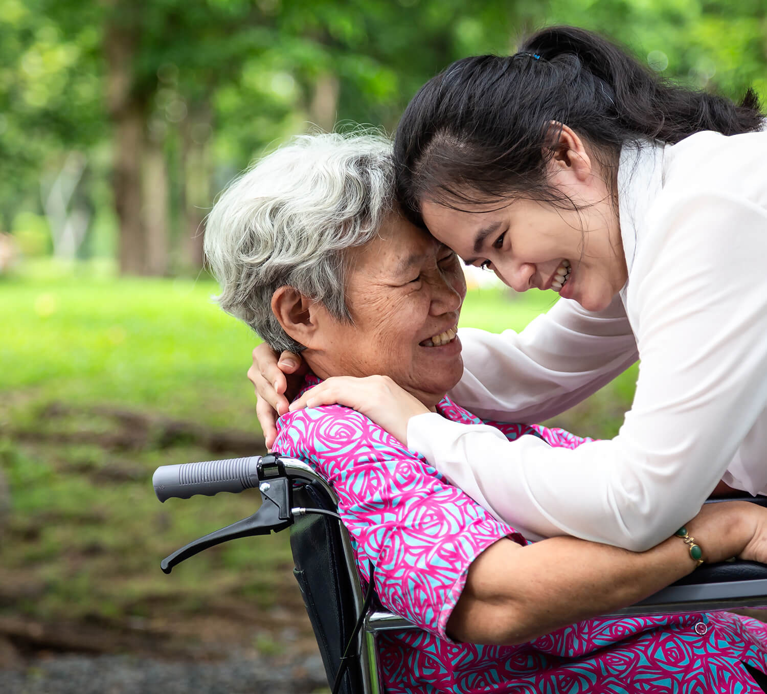 Elderly woman in wheel chair hugging young woman